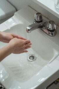 Person Washing Hands on Washbasin